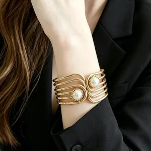 Close-up detail of a vintage gold geometric cuff bracelet with two large pearls