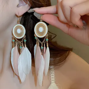 Close-up of Bohemian long feather earrings with turquoise beads and gold finish.