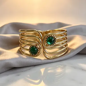 Close-up view of a vintage gold geometric cuff bracelet with two green gemstones