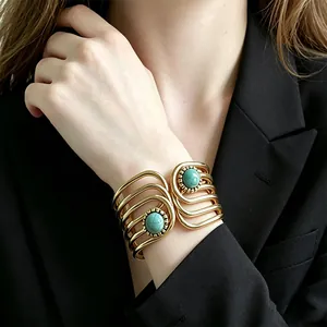 Close-up of retro gold-tone wide cuff bracelet with dual turquoise stones on model