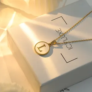 Vue détaillée du pendentif doré avec incrustation de nacre et la lettre L gravée