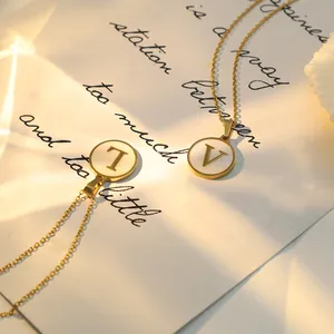 Détail de pendentifs lettres dorés avec incrustation de nacre blanche sous le soleil
