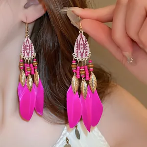 Close-up of bohemian style long feather earrings with gold leaf and bead accents