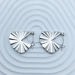 Macro view of silver heart-shaped stainless steel earrings with a radiant pleated texture.
