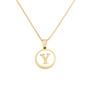 Gros plan d'un collier en or avec un pendentif circulaire en nacre blanche et une lettre Y dorée.