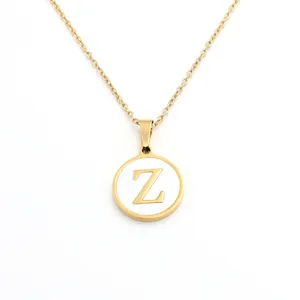 Vue détaillée d'un pendentif circulaire doré avec l'initiale Z sur fond de nacre blanche.