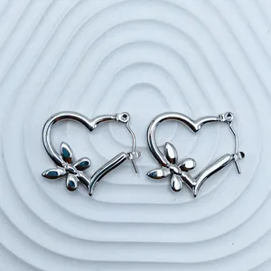 Close-up detail of silver stainless steel heart-shaped hoop earrings with butterfly accents.