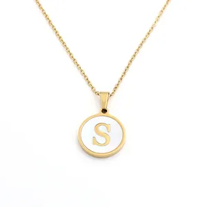 Gros plan d'un collier plaqué or avec un pendentif en nacre blanche et un motif S