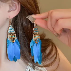 Detail view of bohemian blue feather long drop earrings with ethnic geometric accents.
