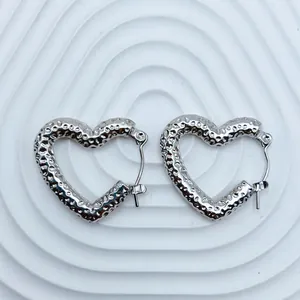 Detailed view of silver heart-shaped stainless steel earrings with unique hammered texture