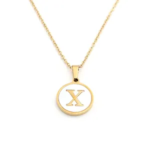 Gros plan d'un collier doré avec pendentif circulaire en nacre blanche et lettre X