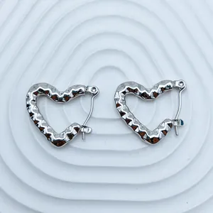 Close-up of silver-tone stainless steel heart hoop earrings with wavy texture.