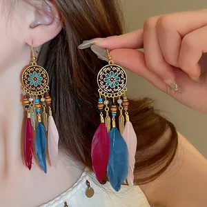 Close-up detail of bohemian long feather earrings with vintage patterns and colorful beads.