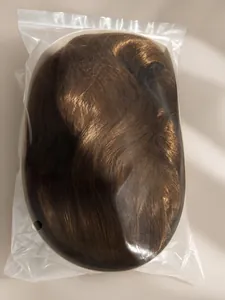 Détail d'une longue perruque synthétique marron emballée dans un sac en plastique protecteur