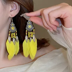 Detailed close-up of Bohemian yellow feather long drop earrings with ethnic beads.