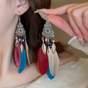 Close-up of bohemian style long dangle earrings with colorful feathers and beads