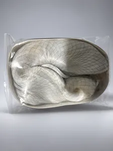 Détail d'une perruque synthétique blanc argenté sous filet protecteur et emballage clair
