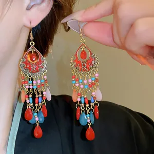 Detail shot of Bohemian retro ethnic long drop earrings with colorful beads and red tassels.