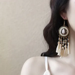 Detail view of bohemian style tassel drop earrings worn by a model in a soft lighting setting.