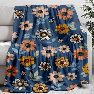 Soft navy blue floral throw blanket with daisy and bee print draped on a white sofa.