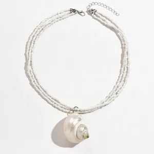 Close-up of bohemian multi-layer white seed bead necklace with natural shell pendant