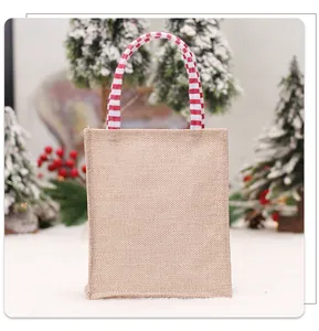 Detail van een kleine kerstcadeautas van jute met rood gestreepte hengsels