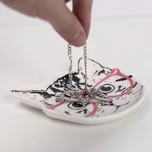 Détail d'un plateau à bijoux en céramique tête de chat avec un collier argenté