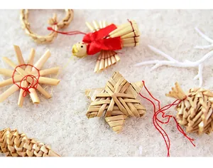 Close-up of traditional straw-woven Christmas ornaments on a white plush surface