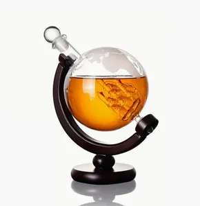 Detail of elegant globe whiskey decanter with internal glass ship on a wooden stand.