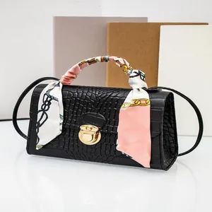 Detailed view of a black crocodile pattern handbag with a colorful silk scarf handle