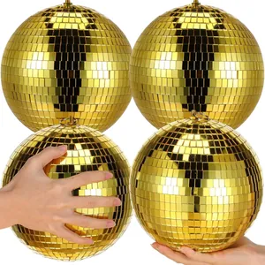 Close-up of golden mirror disco balls showing hand-scale and reflective surface.