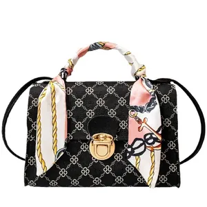 Elegant black patterned crossbody bag featuring a decorative silk scarf wrapped handle