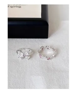 Primer plano detallado de anillos de plata S925 con lazo y corazones rosa de circón.