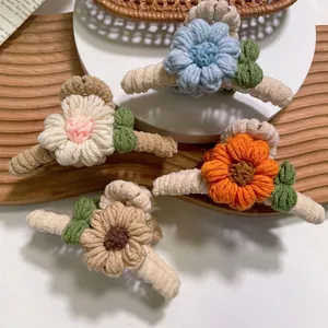 Vue détaillée de quatre pinces à cheveux en forme de fleurs tricotées à la main colorées.