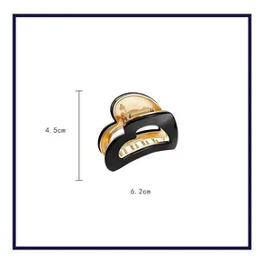 Macro view of a heart-shaped black and gold hair claw clip with dimensions 4.5cm x 6.2cm.