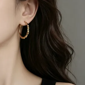 Close-up of elegant gold-plated twisted hoop earrings worn by a model in a detail view