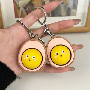 Detalle de un lindo llavero fidget de huevo de dibujos animados con botón amarillo en mano.