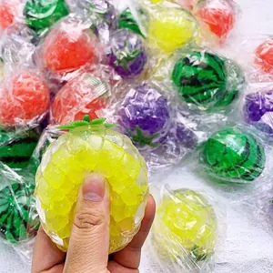 Primer plano de una mano apretando un juguete de descompresión de piña con perlas.