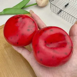 Close-up of two red watermelon slushy stress relief squishy toys held in human hand