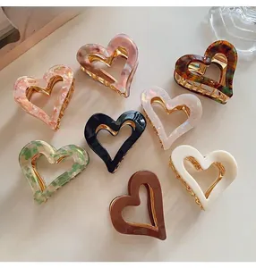 Detailed view of multiple colorful vintage heart-shaped hair claw clips on a light surface