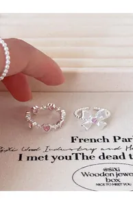 Detalle de anillos de plata esterlina S925 con lazo y corazón rosa en bandeja