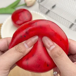 Macro detail of a red watermelon-themed squishy stress ball being squeezed by hands