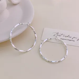 Detail view of elegant silver-colored twisted hoop earrings with a smooth polished finish