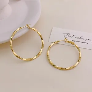 Detail view of elegant gold-plated twisted hoop earrings with a high-polished finish.