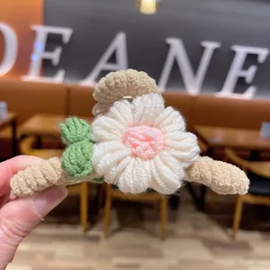 Gros plan d'une pince à cheveux fleur tricotée main avec des détails en laine blanc et rose