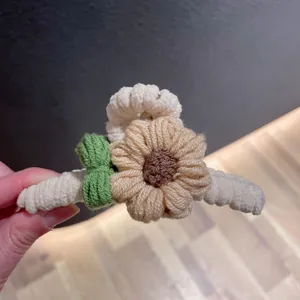 Vue détaillée de la pince à cheveux en forme de tournesol tricoté à la main, texture pelucheuse.