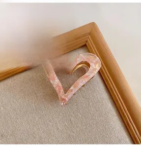 Close-up detail of the pink marbled heart-shaped hair claw clip in a wooden frame