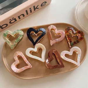 Set of retro heart-shaped hair claw clips in various marbled colors and finishes.