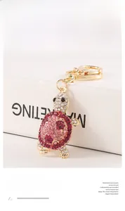 Detailed view of a sparkling pink rhinestone-encrusted turtle keychain on a white box.