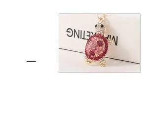 Close-up detail of a sparkling pink rhinestone turtle keychain on a white box display